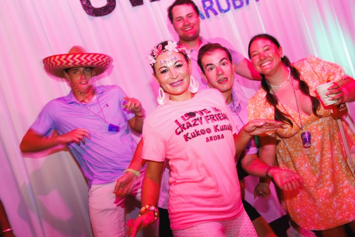 Group of five people posing in a festive setting, one wearing a sombrero.