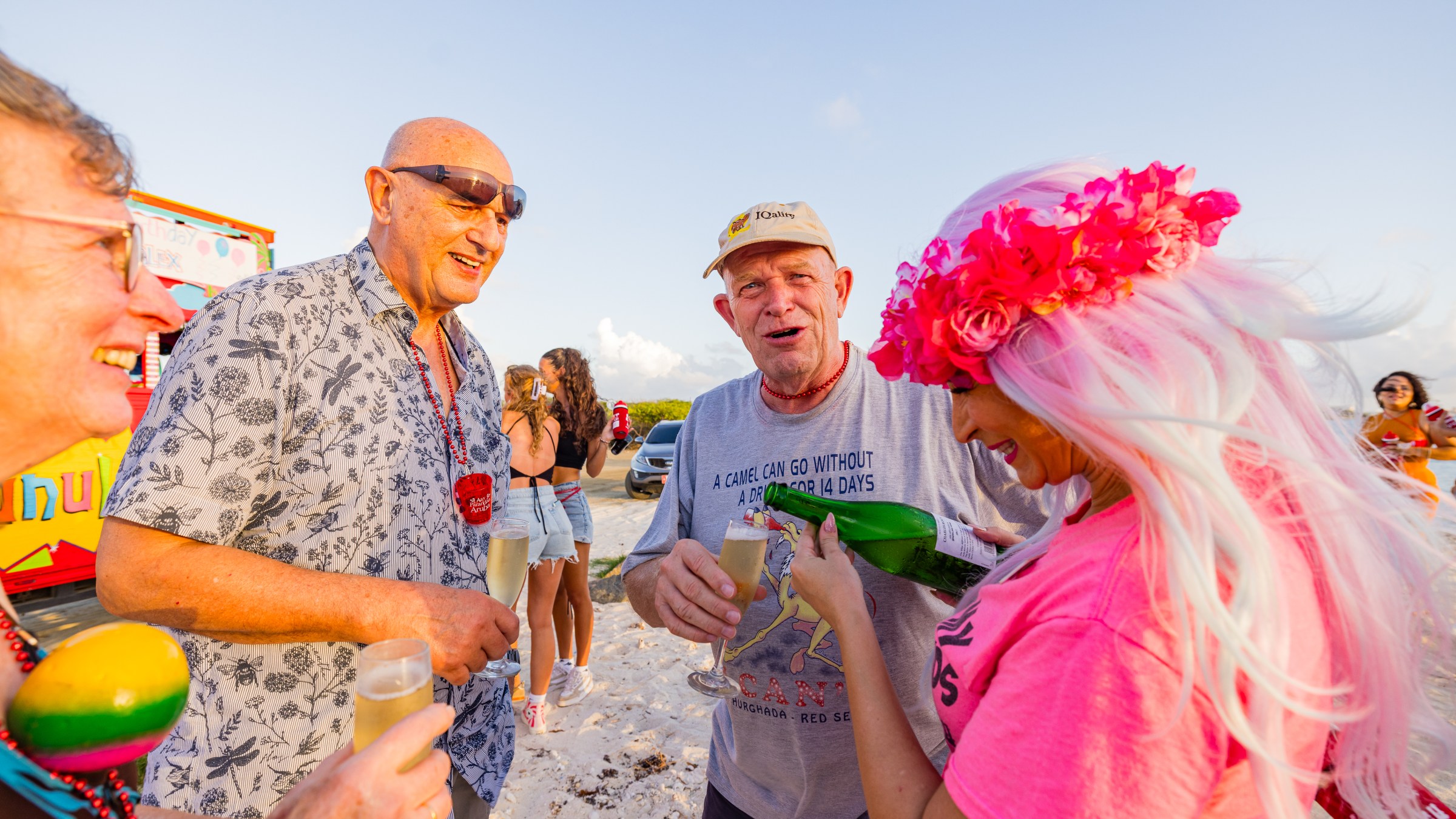 Group of people smiling and holding drinks at a beach party.