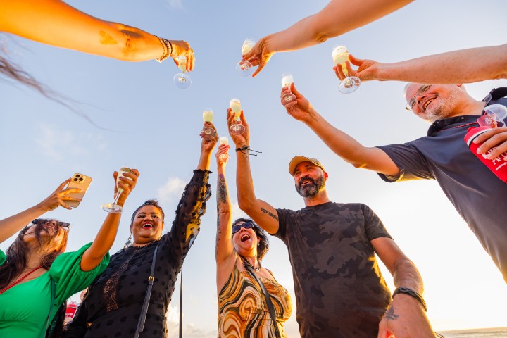 People raising glasses in celebration outdoors under a clear sky.