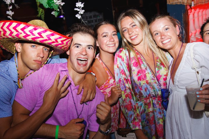 Group of five people smiling at a party, one wearing a colorful sombrero.