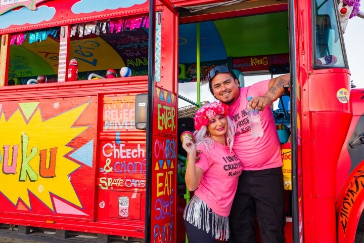 a little girl standing in front of a bus