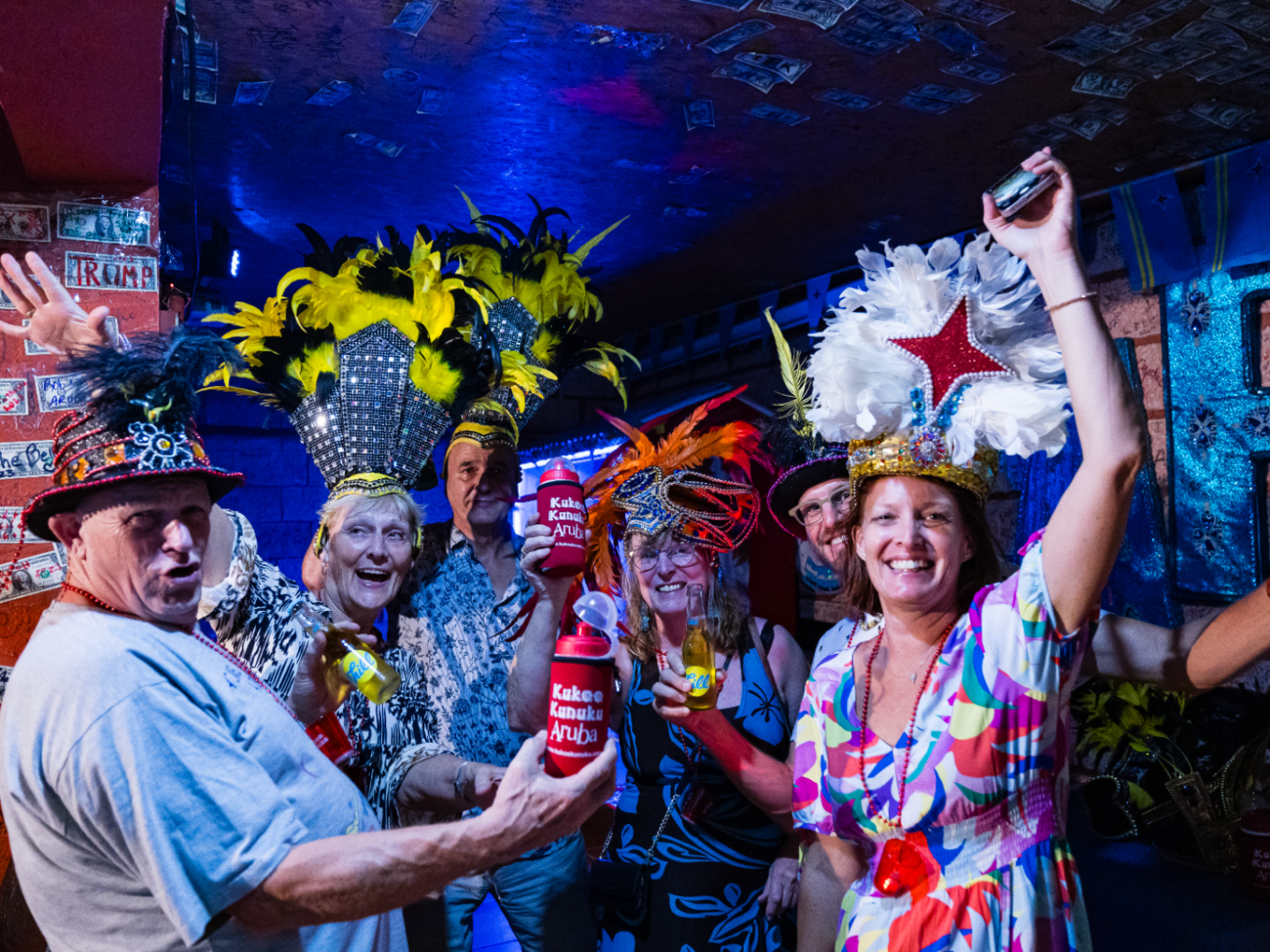 Group of people in vibrant hats celebrating in a colorful room.