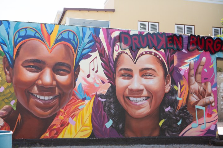 Colorful mural of two smiling people with vibrant headpieces and musical notes.