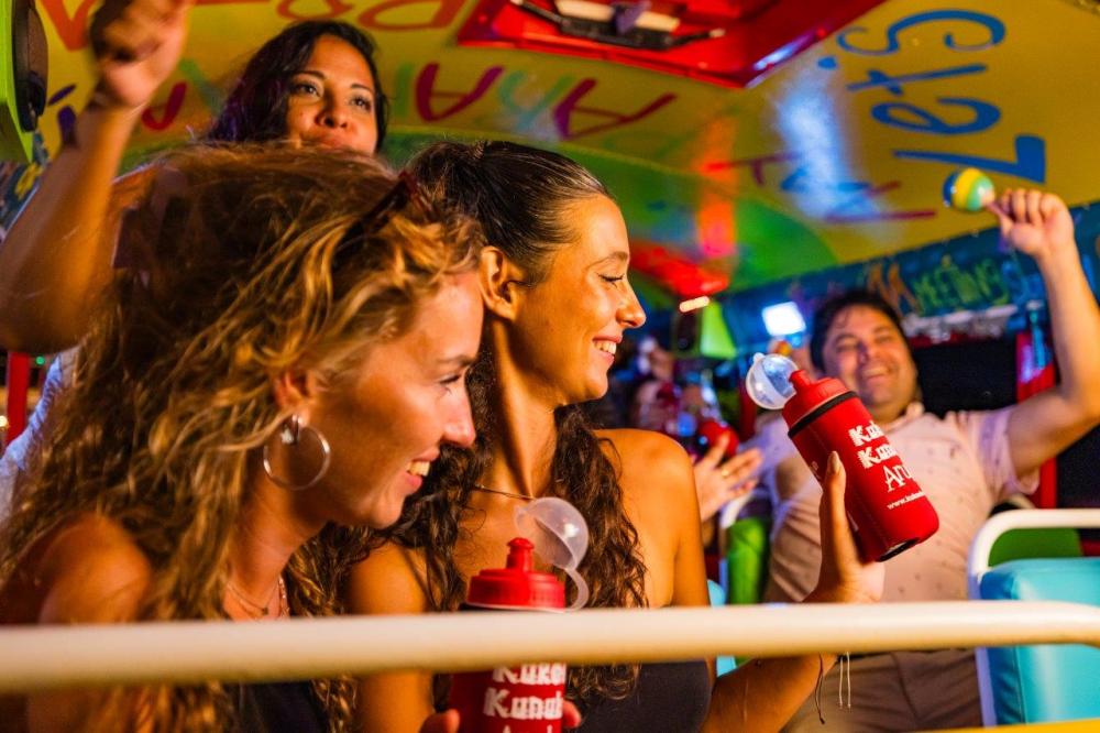 People enjoying a colorful party bus with drinks and music.