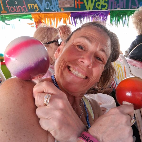 Smiling person holding maracas on a colorful bus with festive decor.